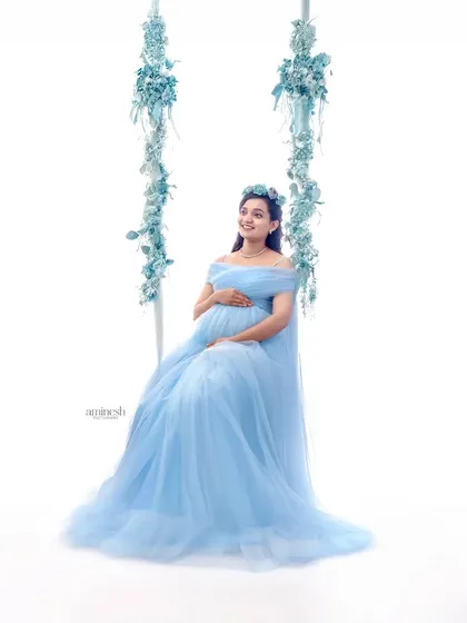 I love creating whimsical and dreamy setups, like this floral swing. Dressed in a flowing light blue gown, the mother-to-be looks ethereal and peaceful against a clean white background.