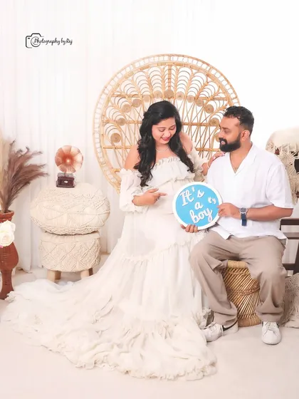A happy gender reveal in our bohemian studio setup, with the couple holding a sign that says "It's a boy!".