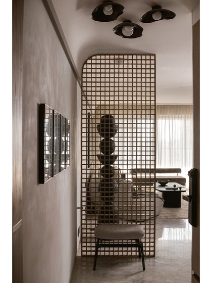The entryway of the Noir Blanc House features a solid wood chequered partition, creating a dramatic sense of arrival and offering a peek at the black totem sculpture within.