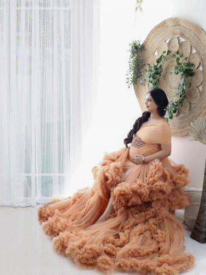 A moment of quiet contemplation in a stunning peach ruffled gown. The soft lighting and boho-inspired set create a warm and inviting atmosphere.