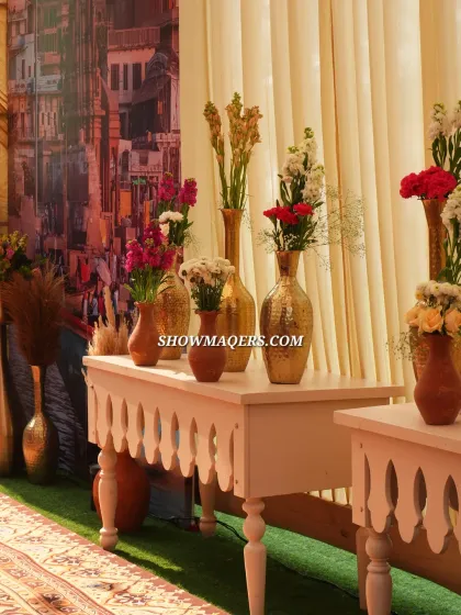 An elegant console table with a mix of traditional and modern floral arrangements against a backdrop of the Banaras ghat painting.