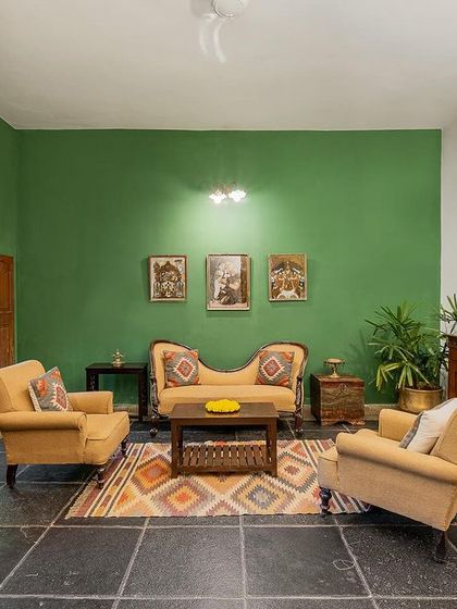 The living area of the Arundati suite, with its vibrant green walls, comfortable seating, and curated antique pieces.