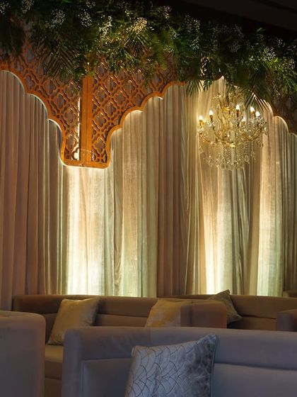 A beautiful view of the lounge backdrop, where chandeliers hang in front of softly lit drapes, creating a layered and luxurious look.
