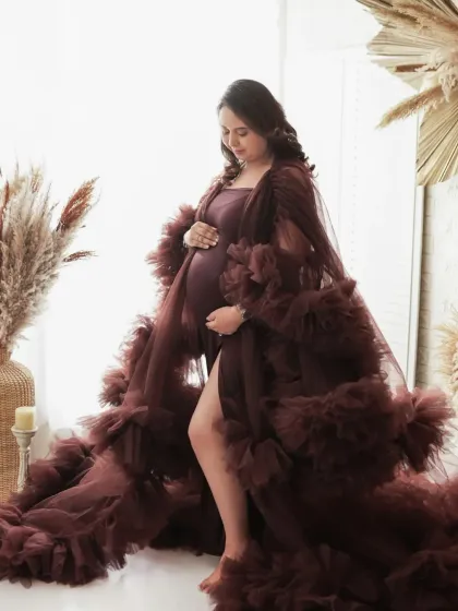 A quiet moment of reflection. This side profile shot beautifully showcases the baby bump, with the soft light and flowing gown adding a touch of grace and elegance.