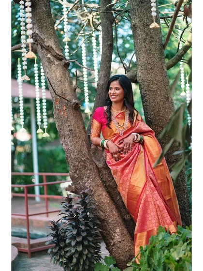 The bride leaning against a tree, lost in a happy thought. This natural, outdoor portrait captures a moment of quiet joy and anticipation.