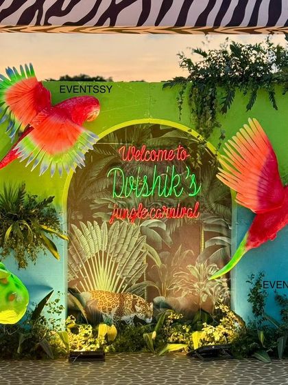 The entrance arch to the 'Jungle Carnival', featuring neon signs and vibrant, larger-than-life parrot props.