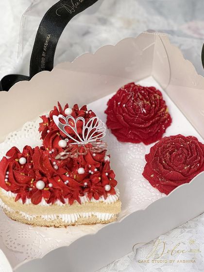 The heart bento cake and chocolate peonies for Valentine's Day, ready to be packed. The vibrant red frosting and delicate butterfly topper make this a truly enchanting gift.