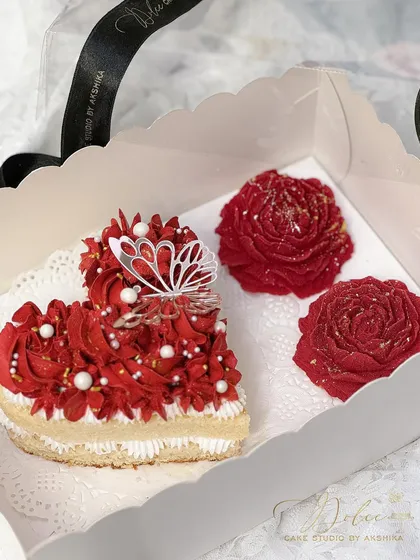 The heart bento cake and chocolate peonies for Valentine's Day, ready to be packed. The vibrant red frosting and delicate butterfly topper make this a truly enchanting gift.