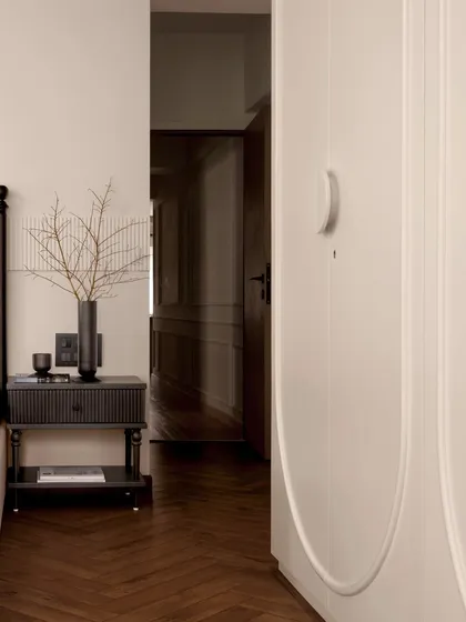 A detail shot of the master bedroom, focusing on the custom wardrobe with its unique curved door design. The clean lines and neutral palette create a sense of calm and sophistication.