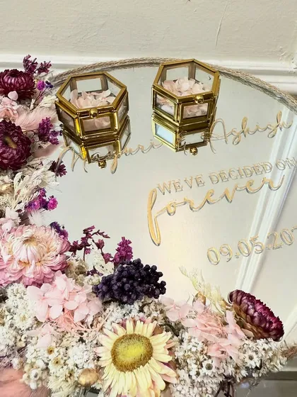 A closer look at the 'Moonflora' mirror ring tray, showing the reflection and the intricate details of the flowers and gold-toned ring boxes.