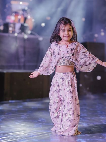 An adorable little girl in a beautiful outfit, ready for her moment in the spotlight. Her grace and smile are what make kids' performances so special.