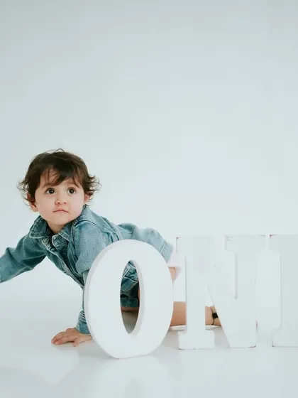 A curious pause during his crawl. The simple denim outfit gives this minimalist first birthday shoot a cool, modern feel.