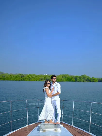 A beautiful wide shot of the couple standing at the bow of a boat, surrounded by blue water and green shores, perfect for a destination pre-wedding album.