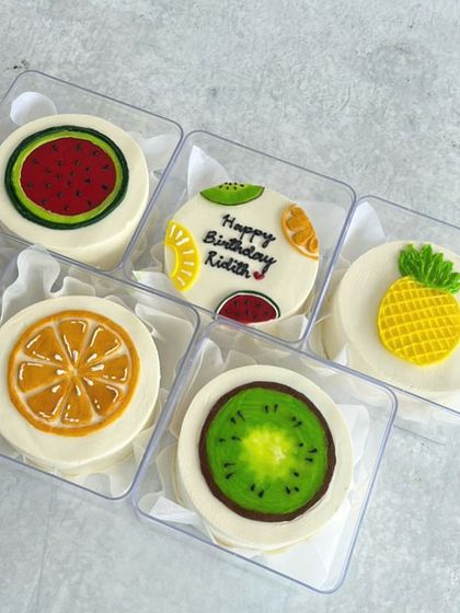 A fresh and fruity set of mini bento cakes, designed to look like a watermelon, kiwi, orange, and pineapple.