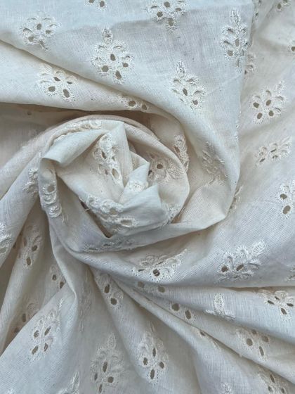 A closer look at the intricate detail of our cutwork cotton fabric. This classic design is perfect for creating breathable and sophisticated outfits.