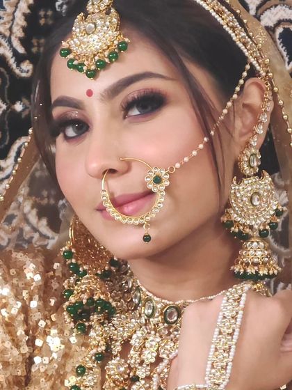 A close-up of a bride in a golden sequin lehenga, complemented by a heavy Kundan and green bead jewellery set.