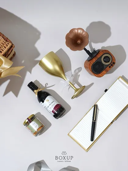 A deconstructed view of the 'Vintage Dreams' hamper, showing the non-alcoholic wine, retro speaker, notepad, and other curated items.