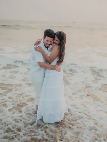 The couple embraces as the waves wash over their feet. This photo captures a romantic and sensory moment, with the sea itself becoming a part of their love story.