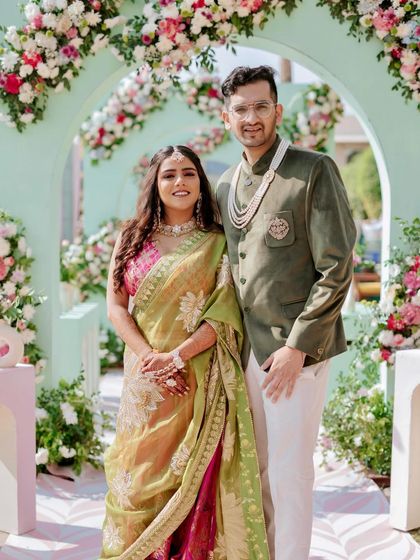 The couple framed by the beautiful mint green arches of their Mehendi entrance, a perfect photo that captures the fresh and modern aesthetic of their celebration.