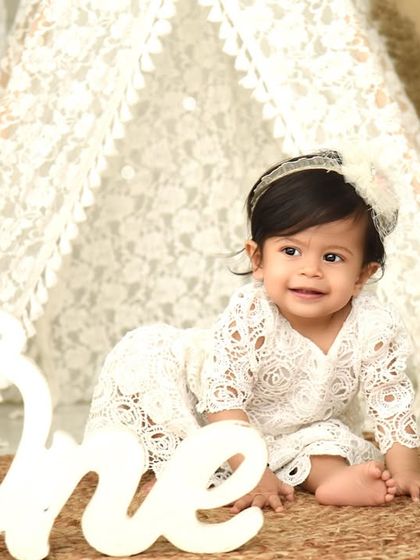 A quiet moment during her boho-themed first birthday shoot. The "One" sign and natural textures create a simple yet beautiful portrait.