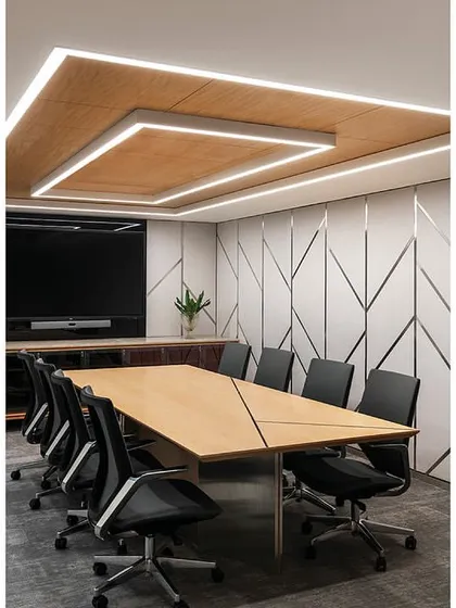 A meeting room in 'The Layered Office' showcases a consistent design language used across all floors. It features fabric paneling with stainless steel inlays and a custom Corian-finished table, with a TV concealed behind a back-painted glass panel.