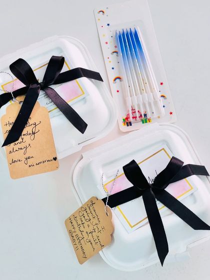 Make it personal with a handwritten note. This option shows two bento boxes wrapped with classic black ribbons and custom gift tags.