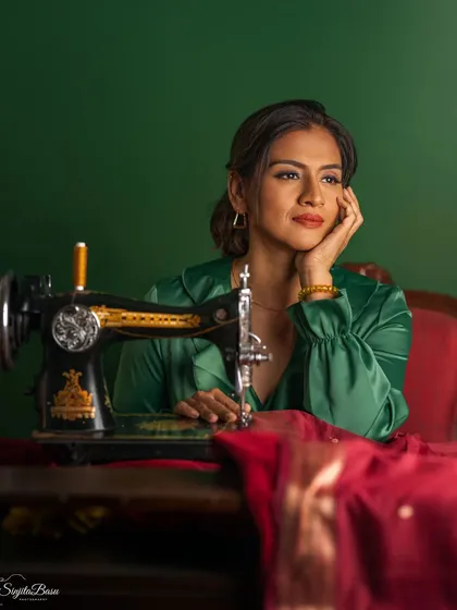 A portrait that tells a story of creativity and heritage. The vintage sewing machine is not just a prop; it's a symbol of craft and tradition. The rich green and red tones, combined with the thoughtful pose, create a deeply narrative and nostalgic image.