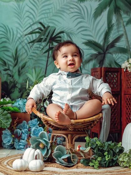 This little pumpkin is sitting like a pro. The tropical leaf background and wicker chair create a stylish and modern sitter portrait.