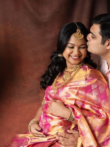A sweet kiss and a happy smile. This intimate moment captures the joy of the parents-to-be during their traditional saree maternity shoot. The rich fabrics and colors make the photo feel so warm.