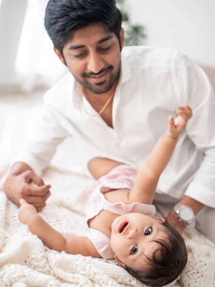 A playful moment between a father and his baby girl on a soft blanket.