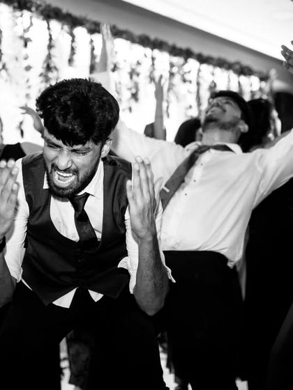 The raw energy of the Sangeet dance floor captured in a dynamic black and white photo, showing guests completely lost in the music.