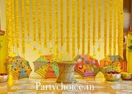 A detailed shot of our yellow-themed Haldi stage. You can see the low wicker stool for the ceremony, brass bowls for turmeric paste, and colorful umbrellas, all arranged to be both functional and aesthetically pleasing.