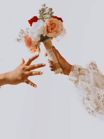 A minimalist and creative take on the bouquet shot, focusing on the hands and the flowers against a clean white background.