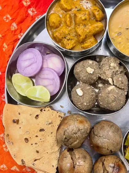 A top-down view of our authentic Rajasthani thali, showcasing a variety of dishes including Masala Gatta, dal, bati, and churma.