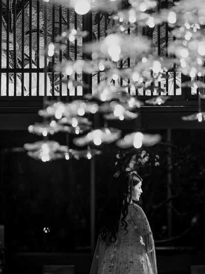 A black and white artistic shot of the bride at her Sangeet. The silhouette against the stunning chandelier creates a moody and timeless portrait that focuses on form and light.