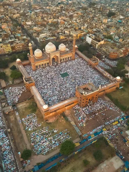 An angled aerial shot that emphasizes the grandeur of the mosque against the urban landscape.