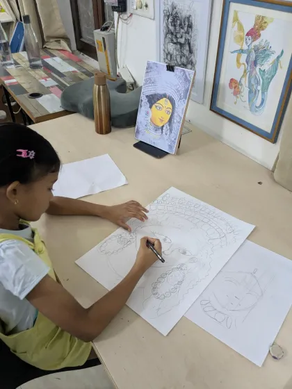 The process begins with a single line. Here, Naomika is carefully sketching the intricate details of her Durga Ma drawing before bringing it to life with watercolors.