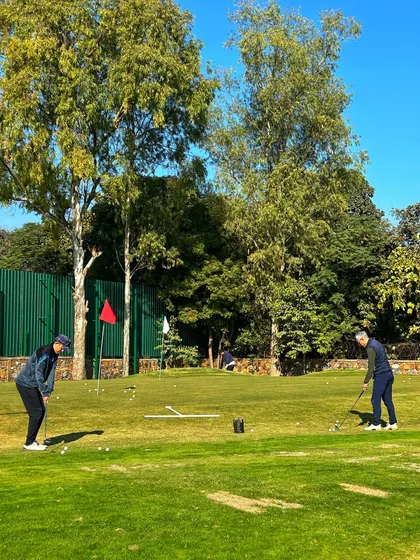 Two golfers practice their chipping and pitching on the lush grass of our short game area.