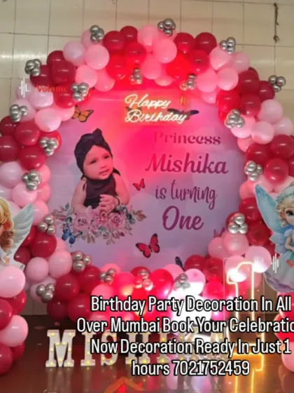 An angelic theme for a princess turning one. This red and pink decoration includes a custom backdrop with the baby's photo, cute angel wing cutouts, and a neon "Happy Birthday" sign.