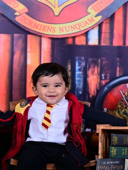 A happy baby dressed as Harry Potter, smiling brightly for the camera.