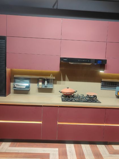The main countertop area of the magenta kitchen, featuring an integrated hob and chimney. The horizontal light strips embedded in the lower cabinets add a unique, futuristic touch.