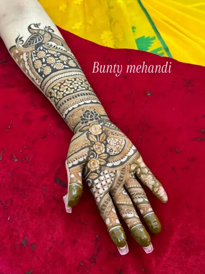 An elegant single-hand design with a peacock at the top and a beautiful floral pattern flowing down the arm.