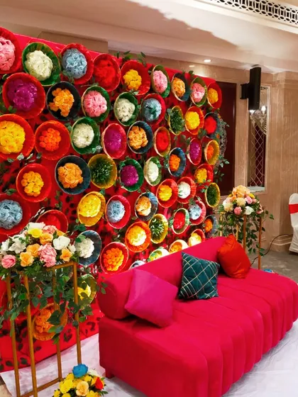 A unique and colorful backdrop for a Mehendi ceremony, created using dozens of baskets filled with dyed flowers. This creative and vibrant wall provided a fantastic photo opportunity for guests.