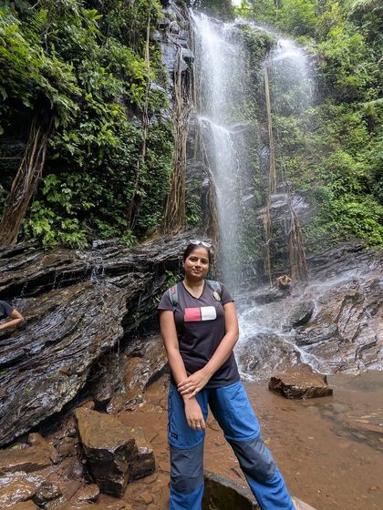 A trekker poses by the rocks at Hidlumane Falls, a perfect photo spot.