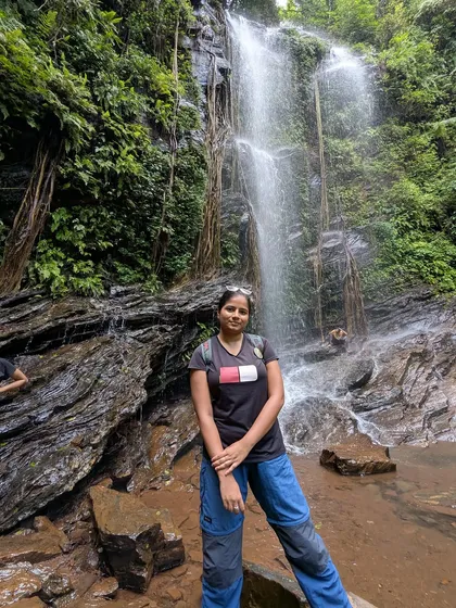 A trekker poses by the rocks at Hidlumane Falls, a perfect photo spot.