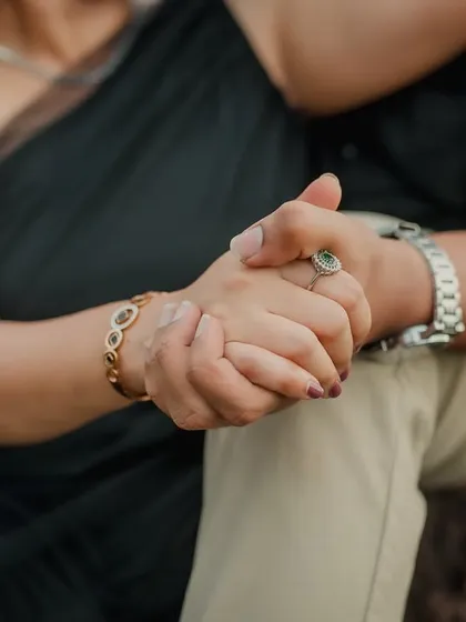 A close-up shot focusing on the couple's intertwined hands. This simple yet powerful image, taken during a beach pre-wedding shoot, symbolizes their connection and unity.