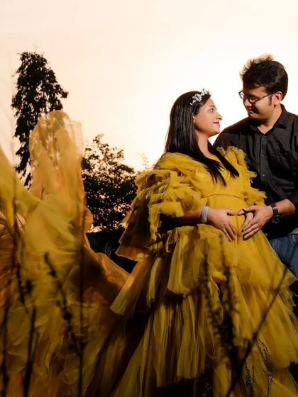 A happy couple posing in our yellow ruffled gown. This dress brings a sense of warmth and sunshine to any maternity photoshoot, whether indoors or outdoors.