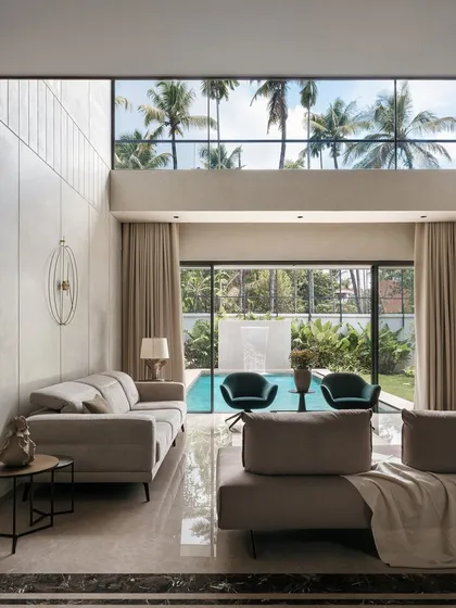 We believe in blurring the lines between indoor and outdoor living. This family area in Villa Shakthi features floor-to-ceiling glass that opens directly to the pool and gardens, creating a seamless flow and filling the double-height space with natural light.