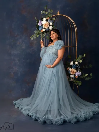 A regal portrait in our elegant birdcage setup. The mom-to-be looks like a queen in a flowing dusty blue gown, surrounded by beautiful floral arrangements.
