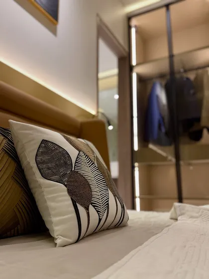 Details make the design. This close-up shot highlights the custom-embroidered cushion and the soft backlighting of the headboard, showcasing our attention to the small touches that elevate a space.